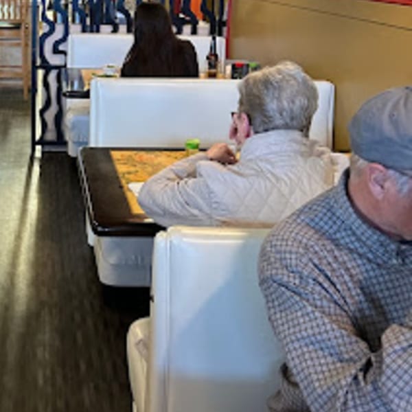 Diners seated in white booths at Tokyo Garden, with a man in a plaid shirt in the foreground.