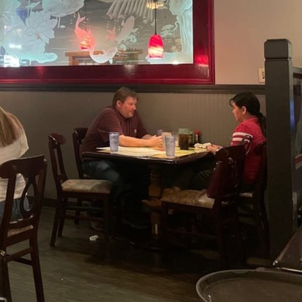 A man and a child sitting at a table in Tokyo Garden, with an ornate Asian-themed wall decoration.